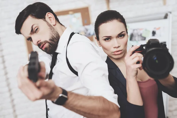 Agencia de detectives privados. Mujer posando con cámara, hombre posando con pistola . — Foto de Stock