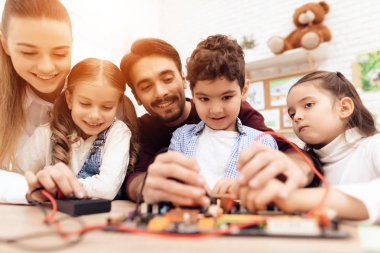 Çocuklar öğretmen ile birlikte bir havya ile iş.