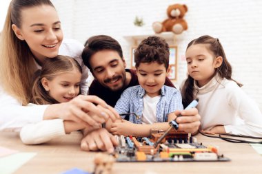 Children together with the teacher work with a soldering iron. clipart