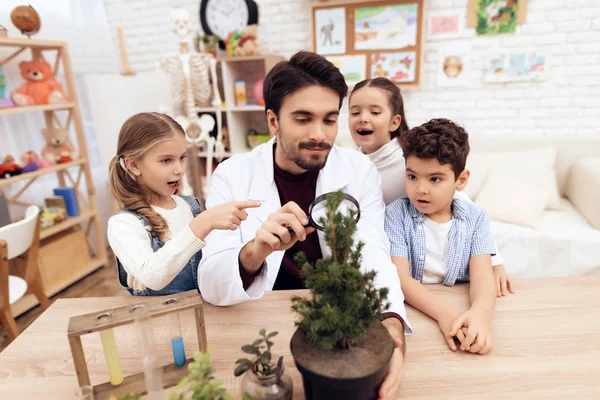 Kinder schauen gemeinsam mit der Lehrerin durch eine Lupe auf eine Pflanze. — Stockfoto