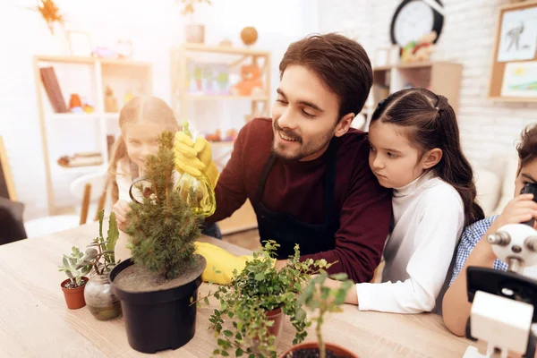 Children together with the teacher look through a magnifying glass on a plant. — Stock Photo, Image