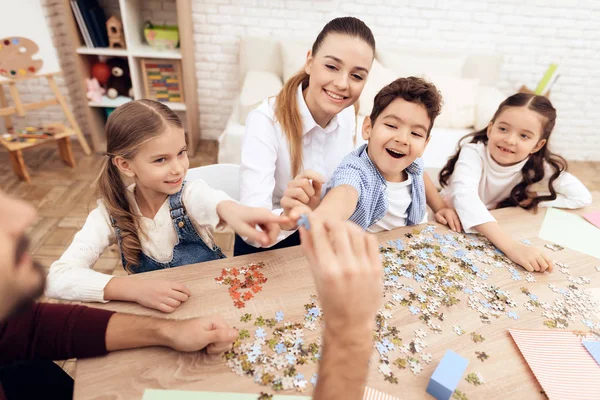 Los niños ponen rompecabezas junto con los adultos . — Foto de Stock