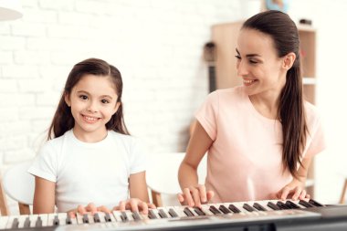Anne ve kız evde synthesizer oynuyorlar. Dinlenmek ve eğlenmek.