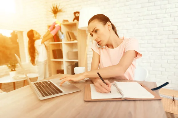 Een vrouw zit aan een tafel in de buurt van een laptop en werken. — Stockfoto