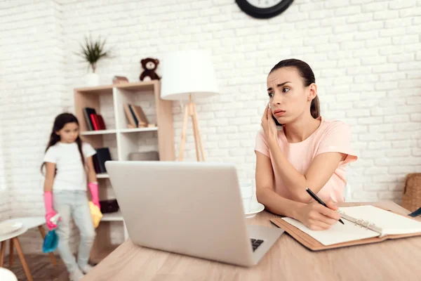 Uma mulher está sentada em uma mesa perto de um laptop e trabalhando . — Fotografia de Stock