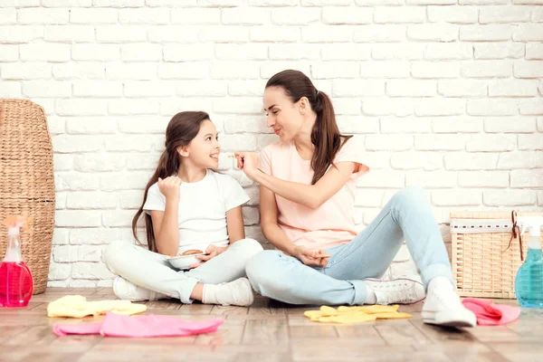 Die Frau und ihre Tochter ruhen sich aus, nachdem sie das Haus ermüdet haben. sie sitzen mit dem Rücken zur Wand auf dem Boden und ruhen sich aus — Stockfoto