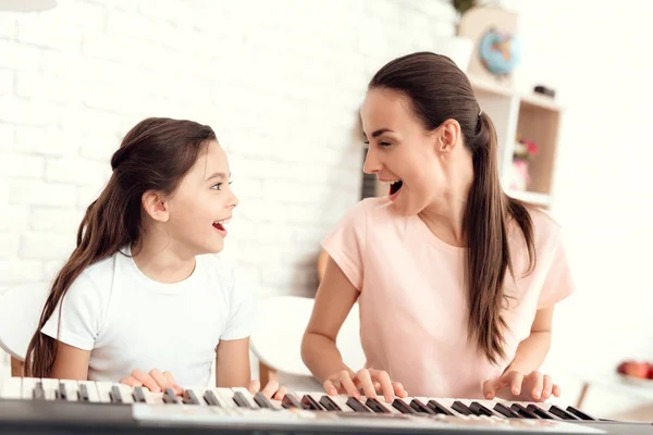 Mãe e menina estão tocando o sintetizador em casa. Eles descansam e se divertem . — Fotografia de Stock