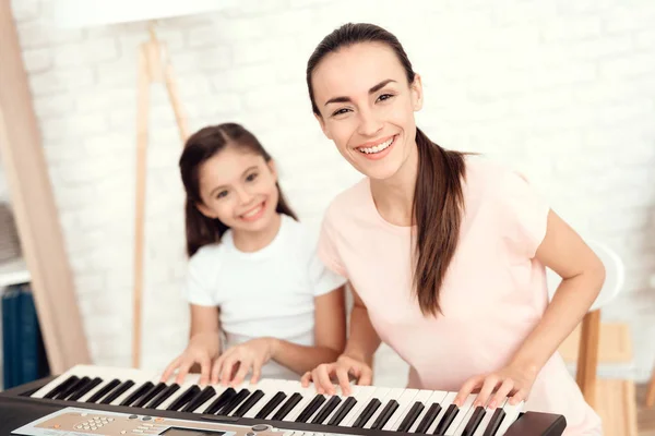 Maman et fille jouent au synthétiseur à la maison. Ils se reposent et s'amusent . — Photo