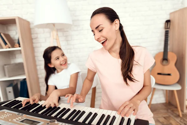 Mamá y niña están tocando el sintetizador en casa. Descansan y se divierten . —  Fotos de Stock