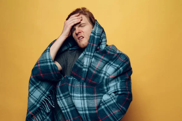 Young Guy Wrapped in Plaid Coughing with Headache