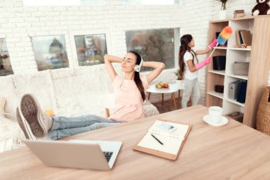 Bir kadın bir dizüstü bilgisayar yakınındaki bir masada oturan ve bacaklarını masanın üstünde dinlenme.