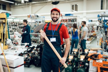 Satıcı ön planda güç araçları mağaza dev çekiç ile poz.