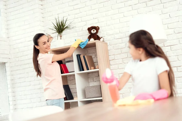 Mamá y su hija están limpiando en casa. Limpie los estantes y la mesa . — Foto de Stock
