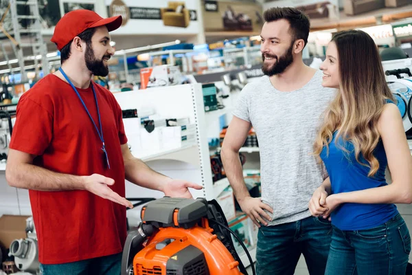 Salesman is explaining details about leaf blower to couple of clients in power tools store. — Stock Photo, Image
