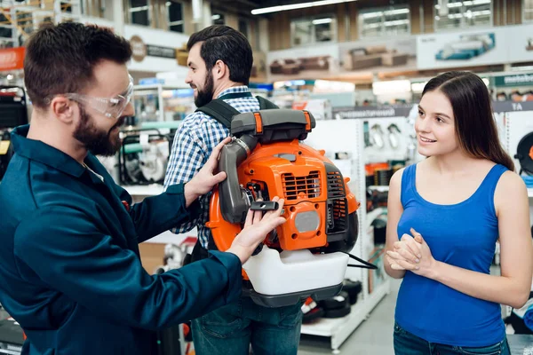 Verkoper vertoont enkele klanten nieuwe industriële bladblazer in power tools winkel. — Stockfoto