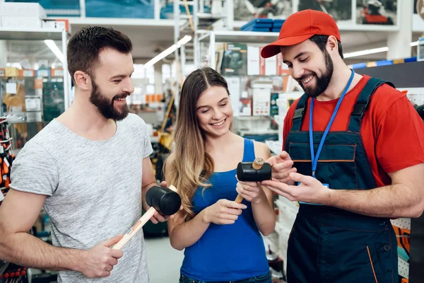 Πωλητής δείχνει δυο πελάτες νέα καουτσούκ σφυριά στο power εργαλεία αποθήκευσης. — Φωτογραφία Αρχείου