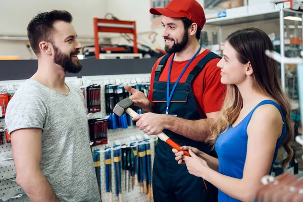 Vendedor está mostrando par de clientes novo martelo na loja de ferramentas elétricas . — Fotografia de Stock