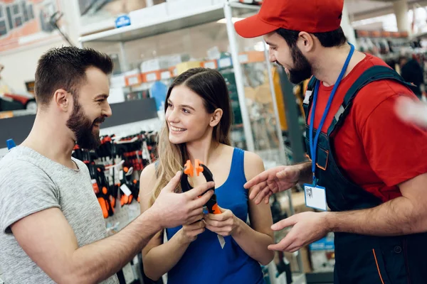 Vendedor está mostrando par de clientes novo alicate na loja de ferramentas elétricas . — Fotografia de Stock