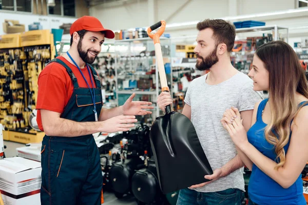 Vendedor está mostrando par de clientes nova pá na loja de ferramentas elétricas . — Fotografia de Stock