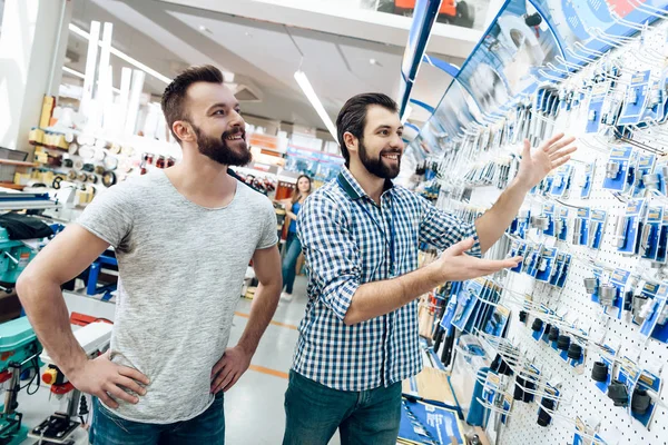Salesman показує бородатий клієнтський вибір обладнання в магазині електроінструментів . — стокове фото