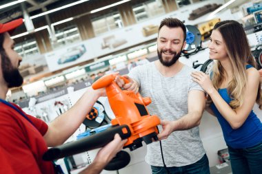 Salesman is giving new leaf blower to couple of clients in power tools store. clipart