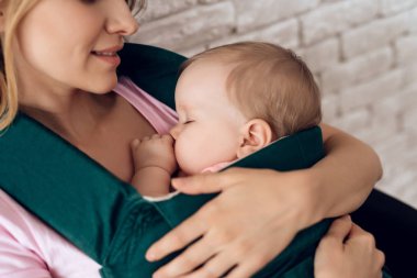 Genç Anne holding uyuyan bebek bebek askı içinde.