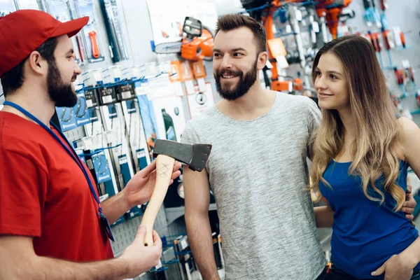 Venditore sta mostrando coppia di clienti nuova ascia nel negozio di utensili elettrici . — Foto Stock