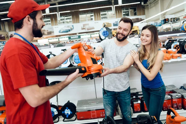 Vendedor está dando nuevo soplador de hojas a un par de clientes en la tienda de herramientas eléctricas . — Foto de Stock