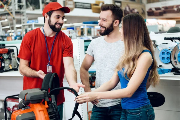 Par klienter diskuterar lövblåsare med försäljare i power tools butik. — Stockfoto