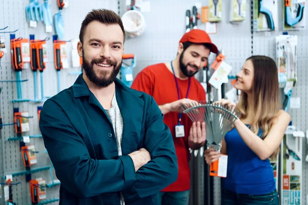 Two salesmen are showing female client new rake in power tools store. — Stock Photo, Image