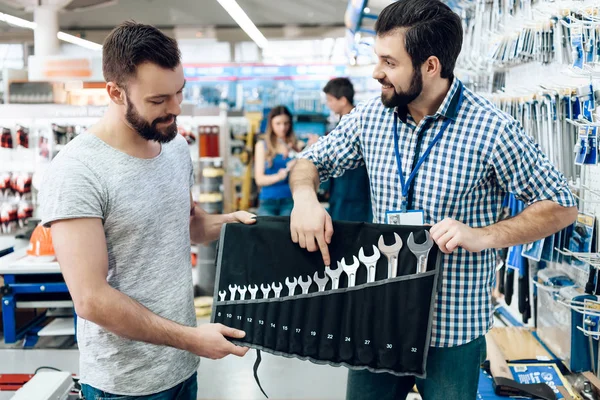 Vendeur montre barbu jeu de clés client dans le magasin d'outils électriques . — Photo