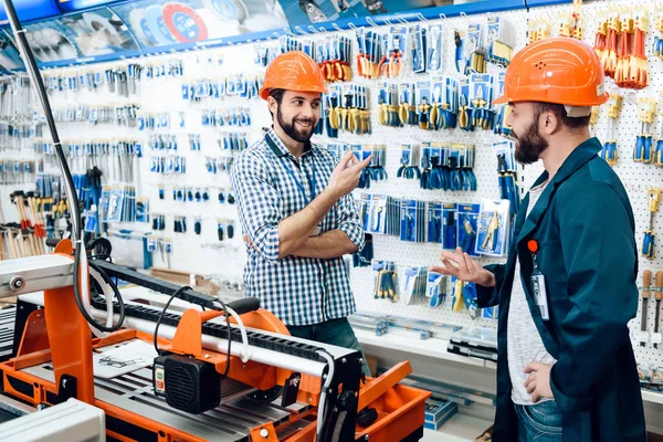 Dwóch sprzedawców dyskutują dobór sprzętu w pobliżu maszyny do obróbki drewna w sklepie narzędzia power. — Zdjęcie stockowe