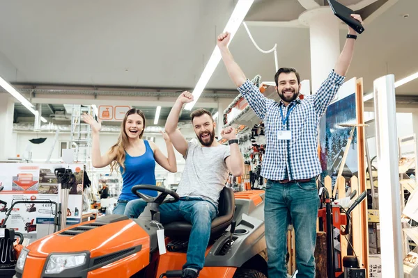 Salesman is showing couple of clients new cleaning machine in power tools store. Three people celebrating new purchase. — Stock Photo, Image