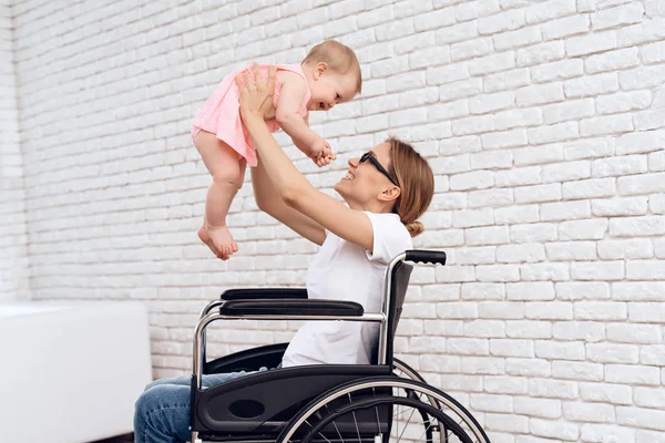 Мати в інвалідному візку грає з новонародженою дитиною . — стокове фото