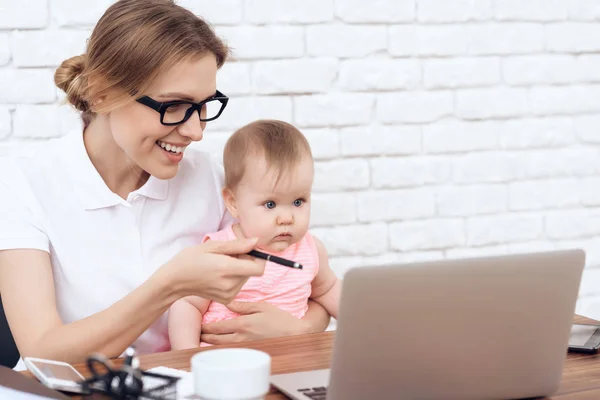 Young business lady entertains cute baby. — Stock Photo, Image