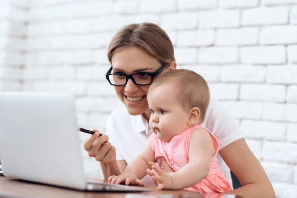 Young business lady entertains cute baby. — Stock Photo, Image