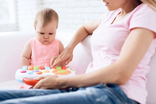 Bonito bebê brincando de brinquedo no sofá com a mãe . — Fotografia de Stock