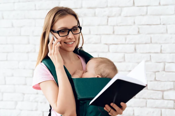 Business woman talking phone and holding newborn. — Stock Photo, Image