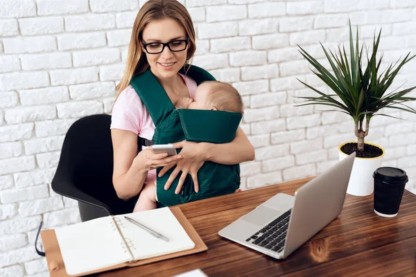 Mulher de negócios trabalhando com recém-nascido em funda de bebê — Fotografia de Stock