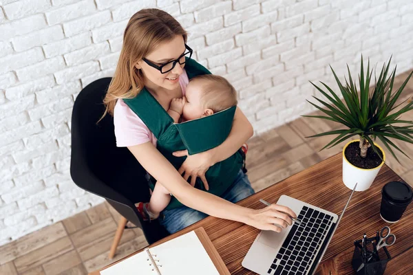 Geschäftsfrau arbeitet mit Neugeborenem im Tragetuch — Stockfoto