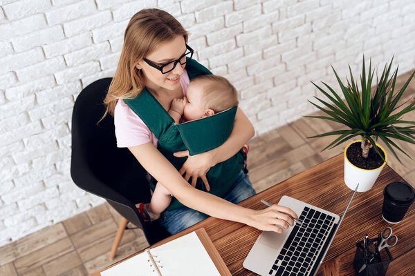 Business woman working with newborn in baby sling