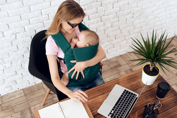Geschäftsfrau arbeitet mit Neugeborenem im Tragetuch — Stockfoto