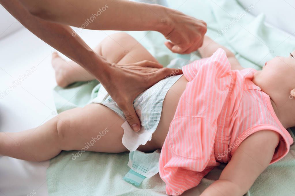 Top view. Mom giving baby diaper change at home.