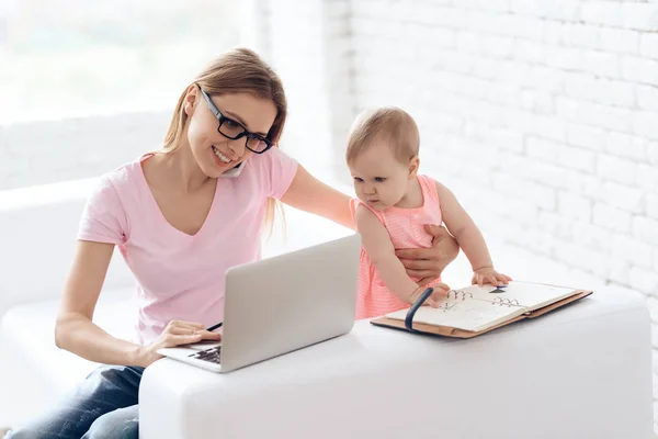 Jovem mãe com bebê trabalhando e usando laptop . — Fotografia de Stock