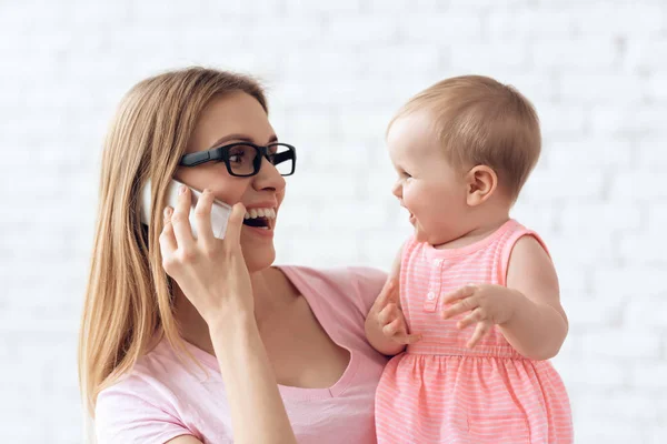 Mãe sorridente com bebê usando smartphone . — Fotografia de Stock