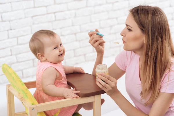 Mãe com purê alimentando pequeno bebê sorridente . — Fotografia de Stock