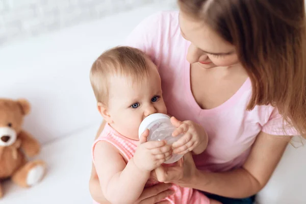 Jovem mãe alimentando bebê leite garrafa casa . — Fotografia de Stock
