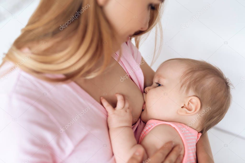Young mother feeding breast newborn baby.