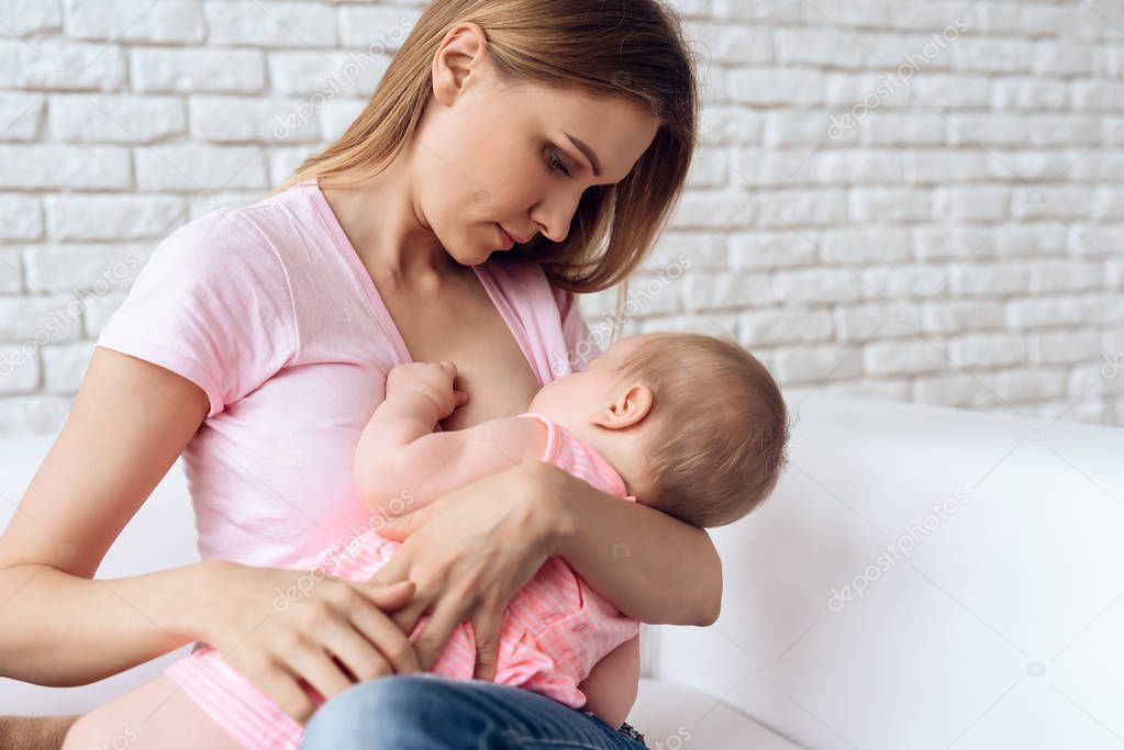 Young mother feeding breast baby.