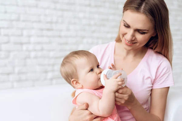 Sorrindo mãe alimentando bebê leite garrafa casa . — Fotografia de Stock